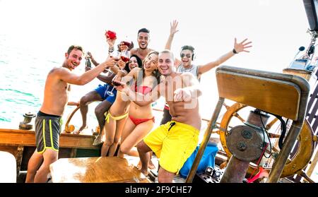 Gruppo di amici milleniali multirazziali che si divertono a fare il tifo alla barca a vela Festa - concetto di amicizia con giovani multirazziali su barca a vela di lusso Foto Stock