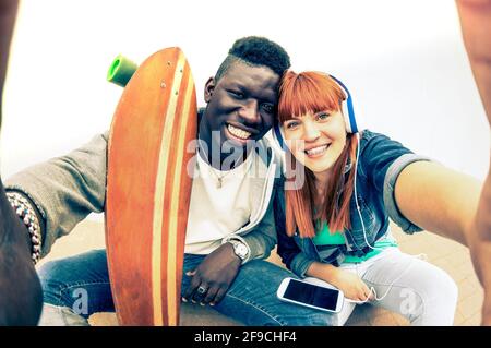 Hipster coppia multirazziale in amore prendendo selfie su sfondo bianco - concetto di divertimento con tendenze alternative della moda e della tecnologia Foto Stock