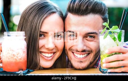 Bell'uomo e giovane donna che sorride sull'happy hour a. Cocktail bar - Coppia di giovani amanti all'inizio dell'amore Storia - fidanzato e ragazza Foto Stock