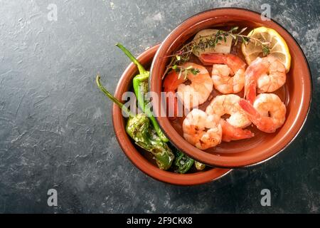 Gamberi e pimientos fritti o peperoni di Padron in ciotole di tapa impilate, antipasto spagnolo tradizionale su uno sfondo di ardesia grigio scuro, spazio di copia, alto a. Foto Stock