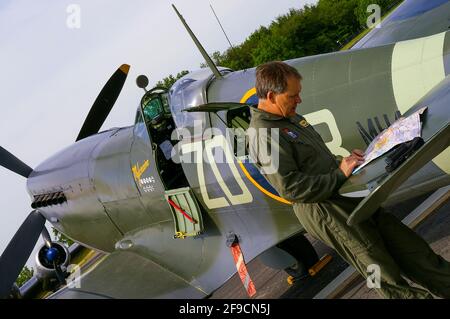 Il pilota Nigel Lamb si prepara al volo in aereo da combattimento della seconda guerra mondiale Supermarine Spitfire IX MH434 a Biggin Hill, Kent, UK. Uso dell'ala come scrivania Foto Stock