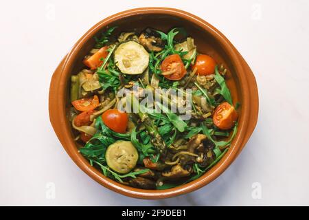 Piatto di pasta mediterranea stagionale con asparagi fritti, zucchine, pomodoro, champigon e rucola Foto Stock