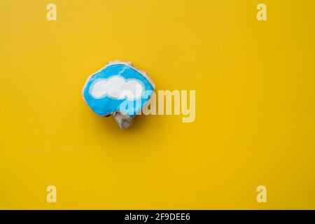 Pietra dipinta con nuvola blu bordata su sfondo giallo AS simbolo per hobby artigianale e felicità Foto Stock