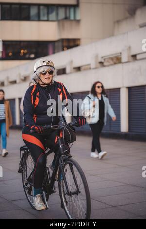 Southbank, Londra | UK - 2021.04.17: Anziana signora in bicicletta sulla Southbank Foto Stock