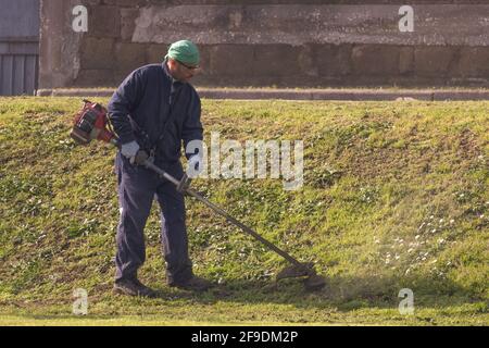 SANTA MARIA CAPUA VETERE, 24 febbraio 2021: Giardinaggio con decespugliatore in un parco pubblico Foto Stock