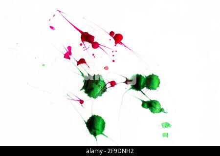 Una goccia verticale di inchiostro cade sulla carta con colori rosso e verde Foto Stock