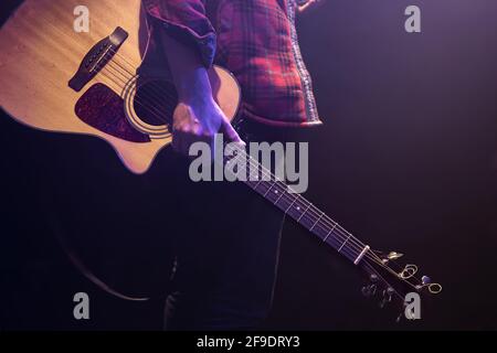 Un uomo che tiene una chitarra acustica nel suo spazio di copia delle mani. Foto Stock