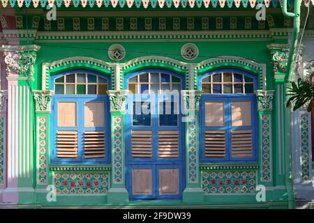 Colorato esterno della bottega Peranakan con facciata verde e antiche persiane in legno blu e bianco alla luce del mattino nella storica Kotong, Singapore Foto Stock