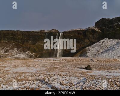 Bella vista frontale della famosa cascata Seljalandsfoss (altezza 66m) situato sulla costa meridionale dell'Islanda vicino alla circonvallazione (Route 1) in inverno. Foto Stock