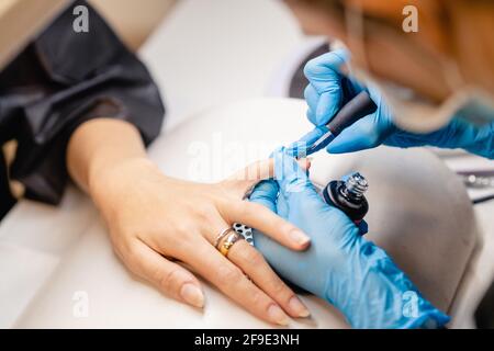 Il manicurista dipinge i chiodi con gel lucidante sui chiodi dei clienti. Foto Stock