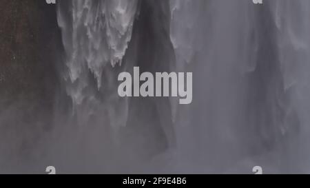 Vista in primo piano della famosa cascata di Skógafoss nel sud dell'Islanda con spray che assomiglia a una tenda d'acqua nella stagione invernale. Foto Stock