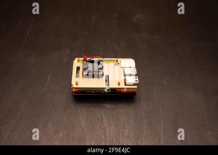 Un computer a scheda singola in un contenitore multicolore con ventola si trova su un tavolo Foto Stock