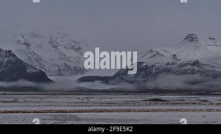 Bella vista della montagna coperta di neve di Öræfajökull nel sud dell'Islanda che scompare nelle basse nuvole con Svínafellsjökull. Foto Stock