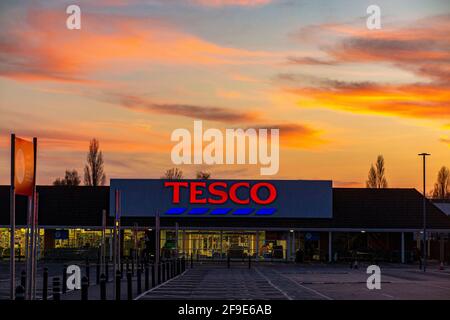 Un grande ramo di Tesco a West Sutton, vuoto durante il blocco del coronavirus con un tramonto draatico dietro di esso Foto Stock