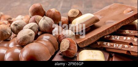 Barrette di cioccolato con noci. Pila di cioccolato alle nocciole. Composizione di barrette e pezzi di latte diverso e cioccolato fondente con nocciole Foto Stock