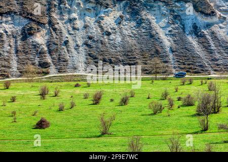 Scoperta della natura in auto . Guidando lungo scogliere rocciose . Prato verde e collina Foto Stock