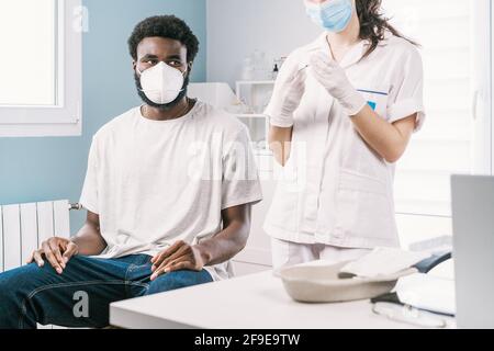 Medico femminile non riconoscibile tagliato in guanti in lattice e visiera protettiva riempimento della siringa dal flacone con il vaccino che si prepara a vaccinare irriconoscibile Foto Stock
