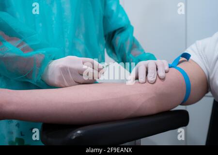 Raccogliere medic irriconoscibile con ago e siringa da cui raccogliere il sangue vena del paziente in ospedale Foto Stock