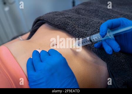Dall'alto del raccolto anonimo estetista professionista che fa l'iniezione per la donna durante il trattamento della cellulite in clinica di bellezza Foto Stock