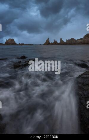 Vista panoramica delle formazioni rocciose sulla spiaggia di Gueirua vicino alla calma Mare sotto il cielo blu nelle Asturie Foto Stock