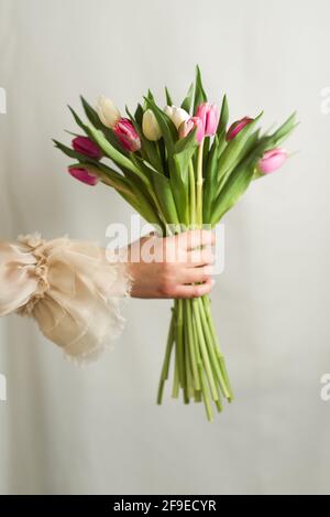 Crop femminile irriconoscibile in abito romantico in piedi con mazzo di teneri fiori colorati Foto Stock
