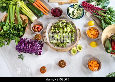Vista dall'alto di verdure intere e tagliate assortite per insalata preparazione su tavola in marmo Foto Stock
