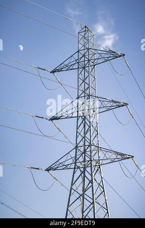 Pilone elettrico con la luna contro un cielo blu, raffigurante la rete nazionale britannica e l'alimentazione elettrica Foto Stock