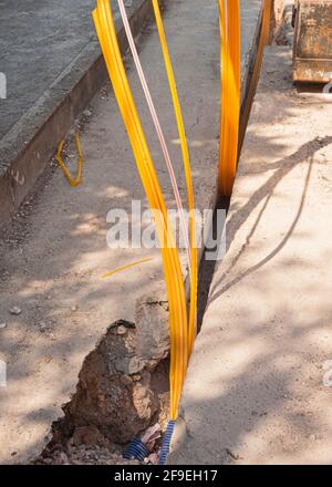 Il lavoratore inserisce cavi in fibra ottica interrati in una micro trincea Foto Stock