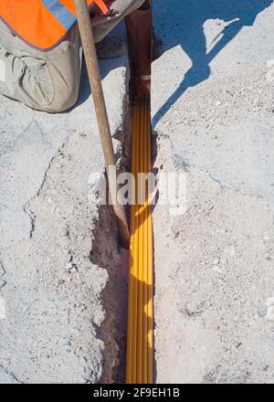 Il lavoratore inserisce cavi in fibra ottica interrati in una micro trincea Foto Stock