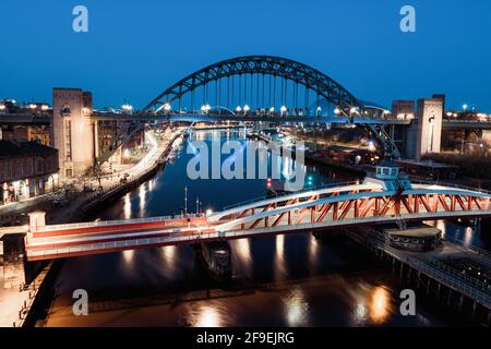 Newcastle upon Tyne UK: 30 marzo 2021: Newcastle Gateshead Quayside di notte, con il ponte di Tyne e lo skyline della città, lunga esposizione durante l'ora blu Foto Stock