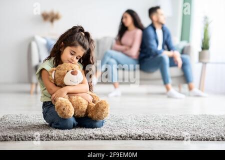 Concetto di conflitti familiari e bambini. Piccola ragazza seduta sconvolto dopo i genitori discutere Foto Stock