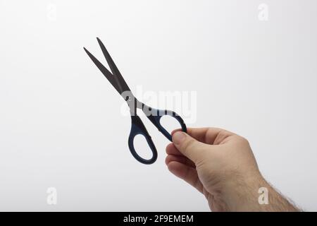 Forbici nelle mani di un uomo. Forbici da cancelleria a mano isolate su sfondo bianco. Foto Stock