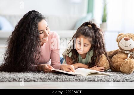 Concetto di sviluppo dei bambini. Libro di lettura di Loving Young Mum alla sua figlia piccola Foto Stock