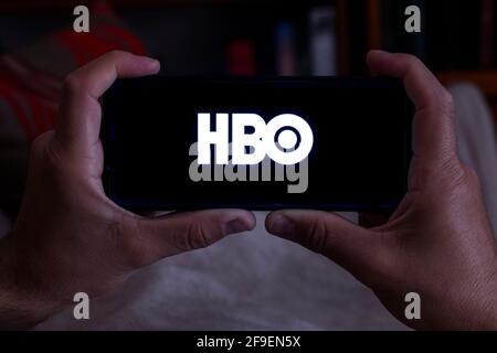 Spagna. 04, 18, 2021. Primo piano di un uomo che tiene uno smartphone con la schermata Home di HBO sul divano di notte Foto Stock