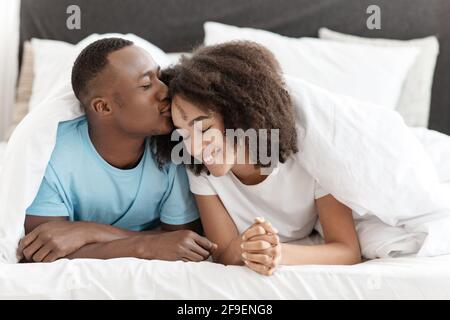 Bella dolce dolce sorridente bella coppia, sotto coperta a letto godendo di tempo libero nel fine settimana Foto Stock