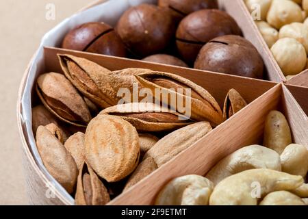 scatola di legno con cellule per diversi alimenti a base di noci per una sana alimentazione proteica primo piano mandorle, nessuno. Foto Stock