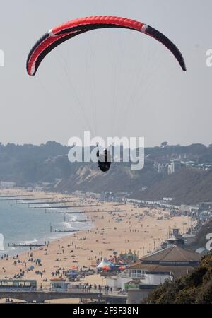 Una persona parapendio sulle scogliere sopra la spiaggia di Bournemouth in Dorset. Data immagine: Domenica 18 aprile 2021. Foto Stock