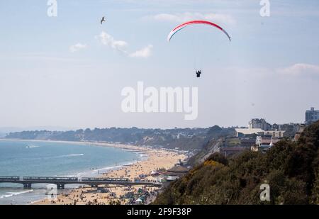 Una persona parapendio sulle scogliere sopra la spiaggia di Bournemouth in Dorset. Data immagine: Domenica 18 aprile 2021. Foto Stock