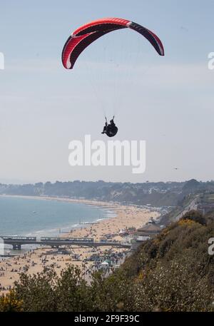 Una persona parapendio sulle scogliere sopra la spiaggia di Bournemouth in Dorset. Data immagine: Domenica 18 aprile 2021. Foto Stock