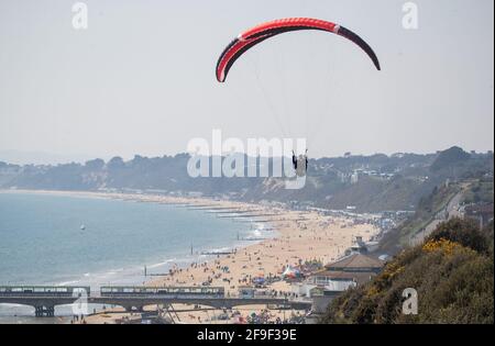 Una persona parapendio sulle scogliere sopra la spiaggia di Bournemouth in Dorset. Data immagine: Domenica 18 aprile 2021. Foto Stock