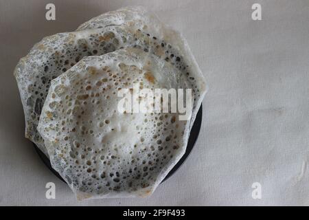 Crepes di riso lacerato o frittelle di riso fermentate fatte con pastella di riso fermentata e latte di cocco. Un piatto preferito per la colazione del Kerala chiamato Appam Foto Stock