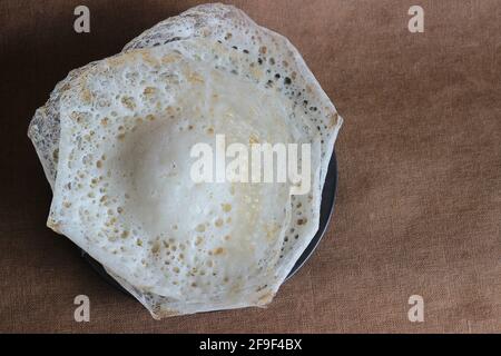 Crepes di riso lacerato o frittelle di riso fermentate fatte con pastella di riso fermentata e latte di cocco. Un piatto preferito per la colazione del Kerala chiamato Appam Foto Stock