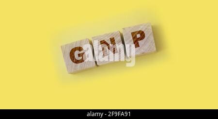 GNP Gross Domestic Product word realizzato con blocchi di legno su sfondo giallo. Foto Stock