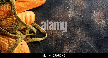 Vari tipi di pane croccante e panini in sacchetti di rete o shopping bag, farina di grano e orecchie su vecchio tavolo marrone di fondo in cemento. Vista dall'alto. Banner. Foto Stock