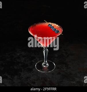 Cocktail cosmopolita di bel colore rosso davanti a uno sfondo nero. Spazio per il testo. Foto per il menu. Foto Stock