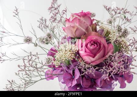 Primo piano di bouquet di due rose rosa e viola diverso e fiori bianchi su sfondo bianco Foto Stock