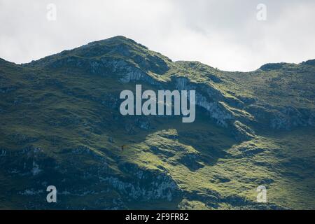 Enormi montagne verdi, bellissime e stupende vette lontane, illuminate dal sole, nel Parco Nazionale dei Picos de Europa, visto da Llanes, vicino al co Foto Stock