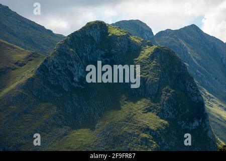 Enormi montagne verdi, bellissime e stupende vette lontane, illuminate dal sole, nel Parco Nazionale dei Picos de Europa, visto da Llanes, vicino al co Foto Stock