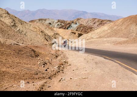 Motociclisti che girano l'angolo su Curving Road presso Artists Scenic Loop Drive al Death Valley National Park Foto Stock