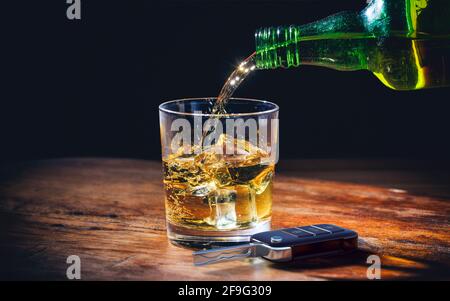 Concetto di guida e bevande. Chiave auto e bicchiere whiskey e bottiglia su sfondo di un bancone di legno. illustrazione 3d. Foto Stock